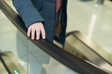 Female hand on escalator handrail, prevention and virus protection concept in mall
