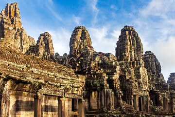 Fototapeta na wymiar Sunrise on some of the face towers in the Bayon temple in Angkor Thom, Angkor. Cambodia. Vertical view.