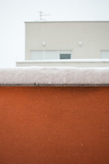 Balcony under winter snow, blurry urban villa in background with copy space for text