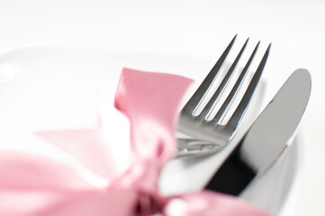 Silver fork and knife tied with pink ribbon