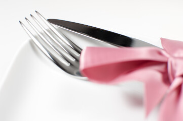 Silver fork and knife tied with pink ribbon