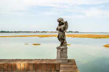 Background on the Venice lagoon with statue of little angel from the island of San Francesco del Deserto, Veneto - Italy