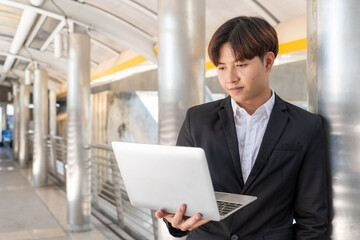 Portrait of handsome business man standing with a laptop outside the office.