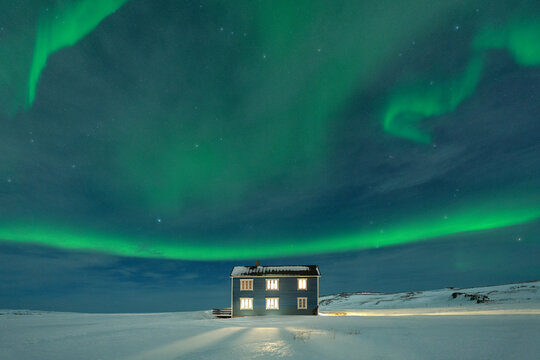 Northern Lights (Aurora borealis) on the illuminated house in the snow, Veines, Kongsfjord, Varanger Peninsula, Finnmark, Norway, Scandinavia, Europe