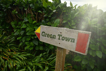 vintage old wooden signboard with text green town near the green plants.