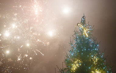 Decorated Christmas tree and fireworks in the sky.