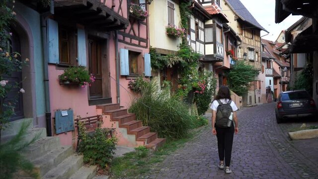 Girl walking through the tiny fairy streets of medieval french village Eguisheim. Alsace, France. Filming in 4K. Cinematic view. 