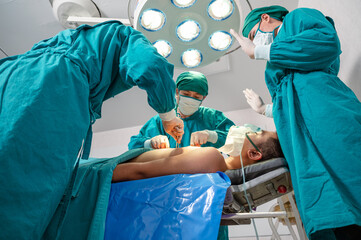 Surgeons team in surgical gown performing surgery a seriously injured patient in operating room