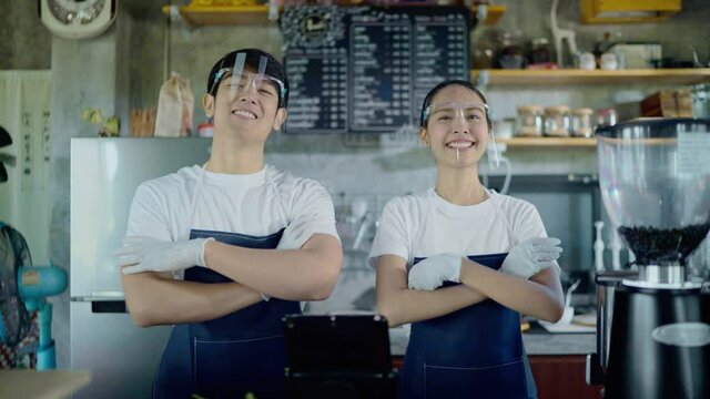 Slow motion portraits of restaurant employees, Asian men and women wearing face shield, smiling and crossed over.
