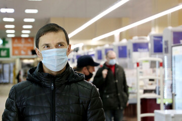 Man in warm clothes and medical mask in a supermarket. Concept of safety during shopping at coronavirus pandemic