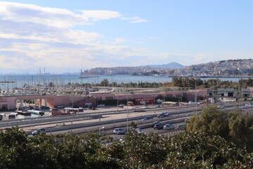 View of the Piraeus city in Athens in Greece. View of the road full of cars & motorbikes. View of the harbor. 