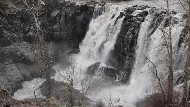  Close up view huge rushing iced over falls in the winter slow motion mist churns up.