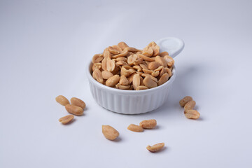 Peanuts in a white ceramic cup on a white background