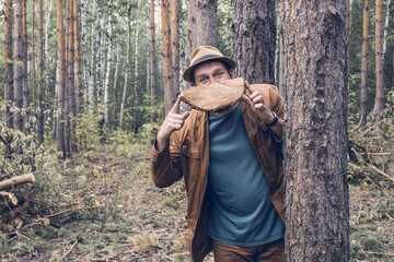 the forest inspection inspector jokingly holds in front of him a segment of a sawn tree