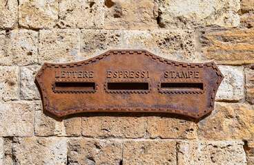Close-up of an antique rusty iron mailbox with three different holes for letters, express and prints (Italian: 