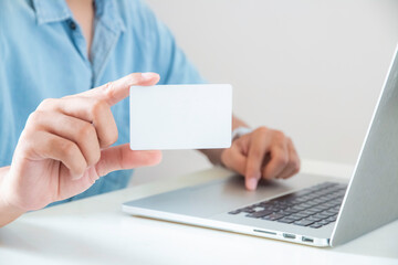 close up hand of man is showing blank card and using laptop.