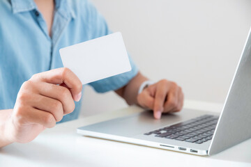 close up hand of man is showing blank card and using laptop.