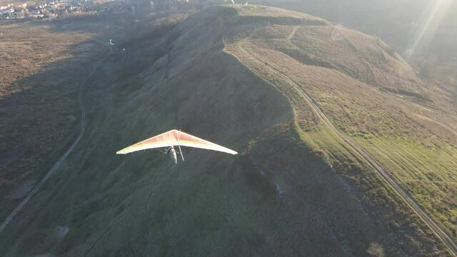 Camera follows colorful hang glider in the air