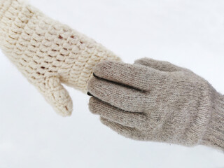 Couple holding hands in gloves in winter season on the background of white snow