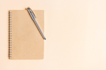 Notebook and pen on brown color background. Top view and copy space.