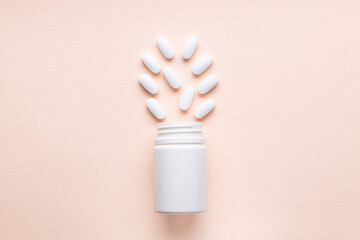white pills near blank bottle isolated pink background. above view. pharmacy concept. outer space