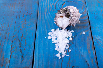 Sea salt scattering out of the seashell against the blue background. Copy space