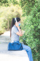 Woman wearing a mask and listening to music in the park