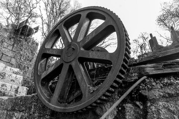 Fototapeta na wymiar A black and white image of a huge rusted dog wheel at an abandoned China clay working in Luxulyan Valley, Cornwall
