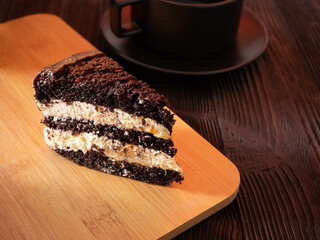 Piece of chocolate cake on wooden plate and black wooden table. Homemade bakery concept for birthday cake or valentine dessert.