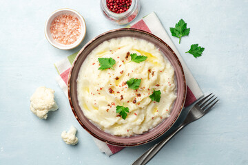 Mashed cauliflower with butter, pink peppercorns and parsley on concrete background