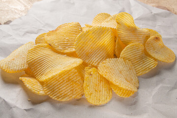 many potato chips lie on a sheet of gray paper