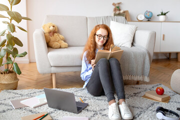 Girl wearing eyeglasses, sitting on the floor, reading book