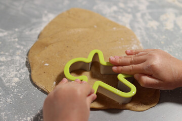 Childmakes gingerbread from dough in cookies forms on the table