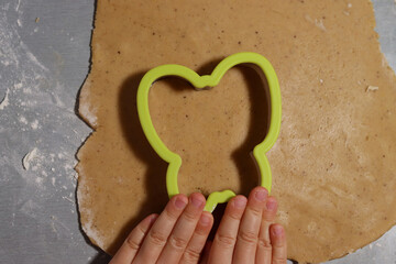 Childmakes gingerbread from dough in cookies forms on the table. Selective focus