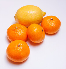 Group of four tangerines and one lemon on a white background.
