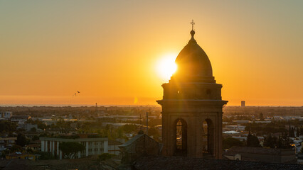 Panorama all'alba di una città vista dall'alto co primo piano del sole dietro alla cupola di un...