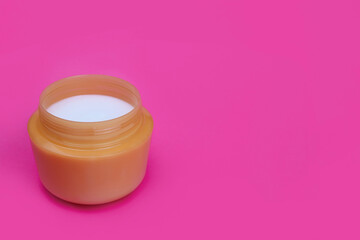 Cosmetic cream in a jar on a pink background