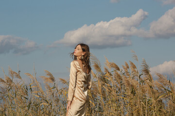 Fashion outdoor portrait of woman in beige silk satin long dress. 