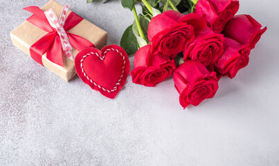 Beautiful red roses, gift box and decorative textile heart on stone background. Valentine's day concept