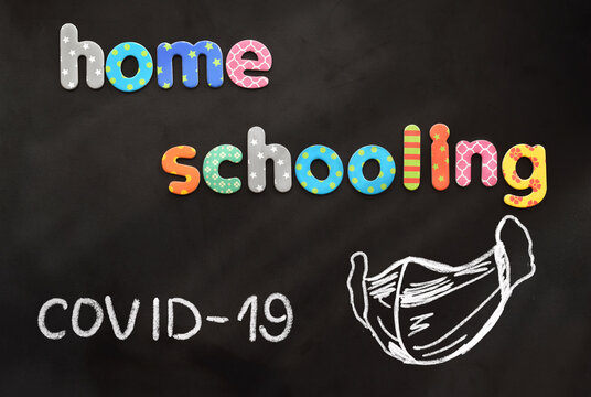 Colorful letters in text "Homeschooling" with drawing of face respiratoy mask on blackboard.