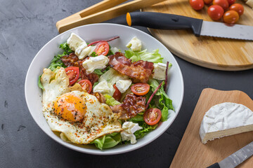 Perfect salad during a ketogenic diet. Full of fats. Fried egg, tomatoes, bacon, lettuce, and cheese. View from above.