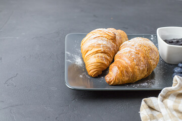 Delicious blueberry croissants on a dark plate. French breakfast.
