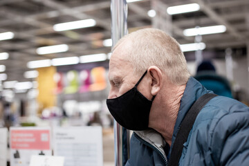 Adult man in a black protective mask in the store. Prevention of viruses