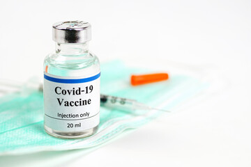 COVID-19 vaccine bottle, vials, syringes and face mask on white background with copy space. Vaccination session and immunity improvement.