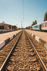 Obraz premium Train tracks of an old and warm village. Colorful train and clear sky.
