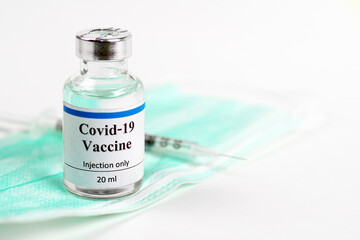 COVID-19 vaccine bottle, vials, syringes and face mask on white background with copy space. Vaccination session and immunity improvement.	