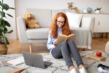 Girl wearing glasses, sitting on the floor, reading book