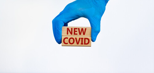 New covid symbol. Hand in blue glove holds wooden blocks with words 'new covid'. Beautiful white background. Copy space. Medical and COVID-19 Pandemic Coronavirus new covid concept.