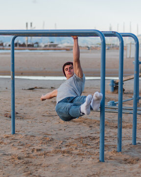 Calisthenics on the parallel bars in front of the beach. One arm front lever exercise.