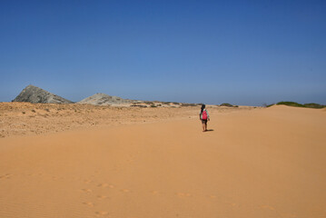 Fototapeta na wymiar Woman walking in the desert of Cabo de la Vela, Guajira, Colombia